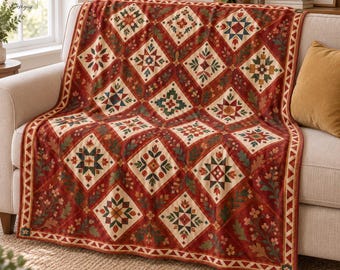 May include: A throw blanket featuring a repeating diamond pattern in shades of deep red, cream, green, and dark blue. The design includes geometric star motifs and floral elements, finished with a triangular border along the edges.