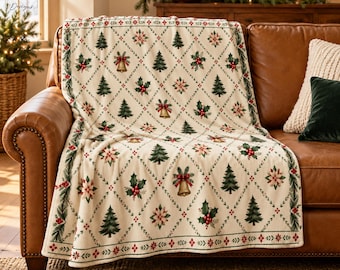 May include: A cream-colored throw blanket featuring a repeating diamond pattern filled with illustrations of green pine trees, gold bells with red bows, holly leaves with red berries, and white poinsettia flowers, finished with a decorative border.