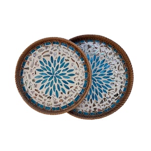 Puede incluir: Dos bandejas redondas decorativas con diseño de mosaico. El centro de cada bandeja presenta un patrón floral azul. El mosaico está rodeado por un borde marrón tejido. Ideales para servir o exhibir.