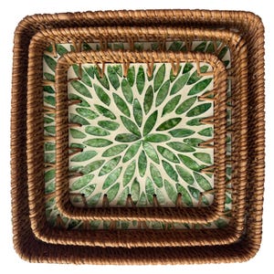May include: Set of three square woven rattan trays. The trays are nested, with a green and white floral design on the interior. The trays are a natural brown color and have a square shape.