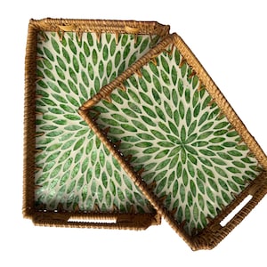 May include: Two rectangular serving trays. The trays have a woven, natural-colored border. The interior of the trays features a white background with a green floral pattern. The trays are different sizes and are nested together.