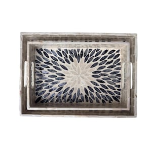 May include: Set of two rectangular serving trays. The trays have a mosaic design with a floral pattern in the center. The mosaic is made of light and dark gray tiles. The trays have handles on the sides.