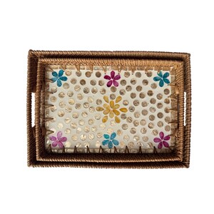 May include: Two rectangular woven trays, one nested inside the other. The interior tray features a cream-colored surface with a dotted pattern and colorful floral accents in blue, yellow, and purple. The trays have handles.