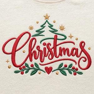 Könnte beinhalten: Ein cremefarbener Stoff mit einer Stickerei, die den Schriftzug Christmas in roter Schreibschrift zeigt. Das Design umfasst den Umriss eines grünen Tannenbaums, goldene Sterne, ein kleines rotes Herz sowie grüne Zweige mit roten Beeren und goldenen Punkten.
