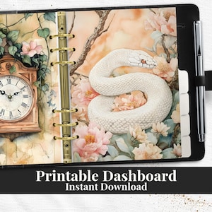 May include: A black planner with a watercolor design featuring a white snake, flowers, and a clock. The text "Printable Dashboard Instant Download" is at the bottom. Includes a pen and tabs.