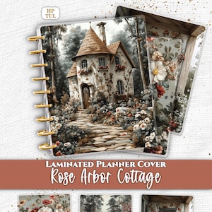 May include: A laminated planner cover set titled Rose Arbor Cottage featuring a stone cottage with a conical roof, a stone path, and floral garden scenes. The covers include gold-colored disc binding rings and the text Everpage and HP TUL.