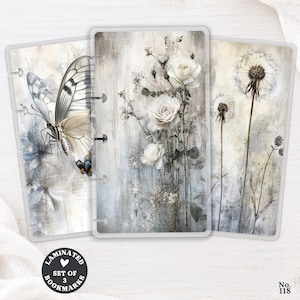 May include: A set of three rectangular laminated bookmarks featuring soft, muted illustrations. One shows a butterfly, another displays white roses, and the third depicts dandelion seed heads. Each bookmark has punched slots along the side.