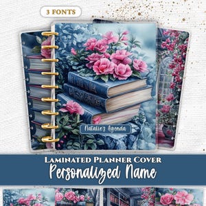 Peut inclure: Une couverture de planificateur plastifiée illustrée d'une pile de livres bleus surmontée de fleurs roses et de feuillage vert. La couverture comporte une étiquette personnalisée avec le nom Natalie's Agenda. Le motif est répété.