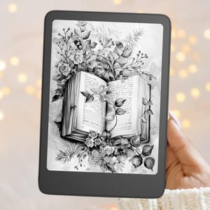 May include: A black e-reader displaying a grayscale illustration of an open book surrounded by detailed botanical elements including roses, leaves, and berries. The screen shows text on the pages of the illustrated book, framed by a dark, thin bezel.