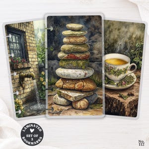 May include: A set of three laminated bookmarks featuring watercolor-style illustrations. One shows a brick wall with a water fountain, another a stack of balanced stones, and the third a steaming teacup. A circular logo reads Laminated Set of 3 Bookmarks.