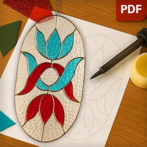 May include: An oval stained glass panel with a floral design in red, turquoise, and white. The panel is on a wooden surface with a pattern template, soldering iron, and wax. The PDF icon is in the upper right corner.