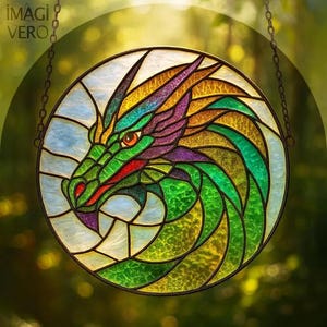 Op de afbeelding: Een rond gebrandschilderd raam met een drakenkop. De draak is afgebeeld in groen, paars, goud en rood, met een gedetailleerd ontwerp. Het raam hangt aan een ketting en heeft de tekst "IMAGI VERO" bovenaan.