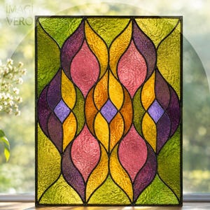 Può includere: Un pannello rettangolare in vetro colorato con un motivo ripetitivo di segmenti curvi a forma di foglia in tonalità vivaci di verde lime, viola intenso, giallo caldo e rosa, uniti da linee di piombo scure con il testo IMAGI VERO.