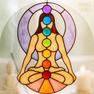 May include: Stained glass suncatcher showing a seated figure with seven coloured chakra symbols. The figure is surrounded by a purple crescent moon shape. The colours include red, orange, yellow, green, blue, indigo, and violet. The image has the text "IMAGI VERO".