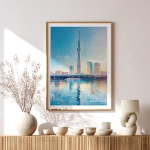 May include: A framed watercolor print of the Tokyo Skytree and surrounding cityscape, reflecting in the water below. The artwork features a blue and white color palette, with a boat on the water and the text "東京スカイツリー" at the bottom.