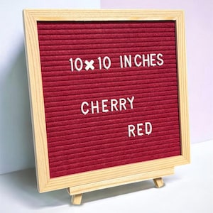 May include: A square felt letter board with a cherry red background and a light wood frame. The board features white plastic letters spelling out 10x10 INCHES, CHERRY, and RED. The board is displayed on a small wooden easel stand.