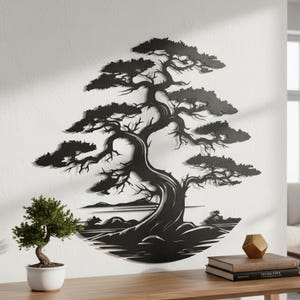 May include: A black metal tree wall art piece. The tree has a thick trunk and branches with detailed leaves. The art is mounted on a white wall. A small bonsai tree in a white pot sits on a wooden table in front of the wall art.