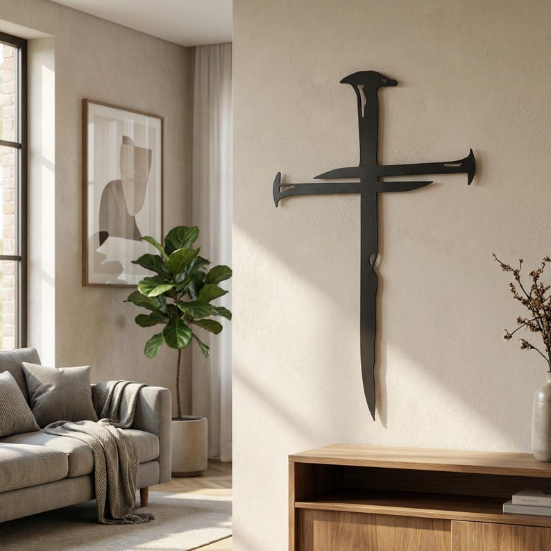 May include: A black metal cross wall art piece with a unique design, featuring stylized nails at the ends of the cross and a textured vertical element. The artwork is mounted on a neutral-colored wall in a living room setting.
