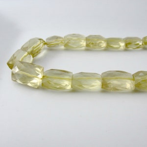 May include: A strand of light yellow faceted gemstone beads. The beads are rectangular in shape and have a smooth, polished finish.