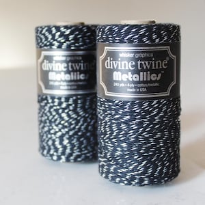 May include: Two spools of black and silver metallic twine. The spools are labeled "divine twine Metallics" and "240 yds 4-ply cotton/metallic made in USA".