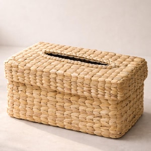 Puede incluir: Funda rectangular para caja de pañuelos de fibras naturales tejidas. La caja tiene una tapa con una abertura rectangular para dispensar los pañuelos. La textura tejida y la paleta de colores neutros le dan una estética rústica y orgánica.