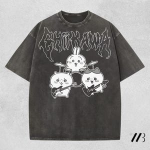 Puede incluir: Una camiseta de manga corta en color gris carbón con un estampado gráfico blanco de tres personajes de dibujos animados tocando instrumentos musicales. El texto CHIIKAWA aparece en una fuente estilizada sobre los personajes.