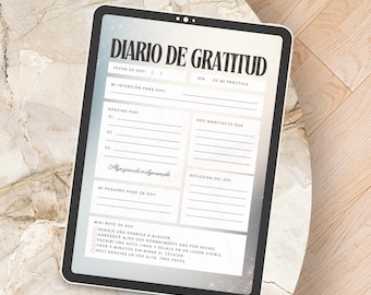 May include: A digital tablet displaying a gratitude journal titled "DIARIO DE GRATITUD" in Spanish. The journal features sections for daily intentions, gratitude, and reflections. The tablet is on a marble-like surface.
