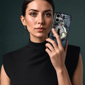 Puede incluir: Una funda de tel&eacute;fono con la silueta de un gato negro sobre una luna creciente, sobre un fondo de estilo vidriera. La funda tiene una combinaci&oacute;n de colores azul oscuro y verde con detalles florales. La funda del tel&eacute;fono la sostiene una persona.