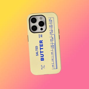 May include: A phone case with a light yellow background and a blue design resembling a butter package. The text on the case reads "SALTED BUTTER" and includes measurement conversions. The case has a black camera module.