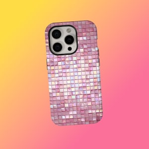 Könnte beinhalten: Eine rosa Handyhülle mit einem Mosaikfliesen-Design. Die Hülle hat ein quadratisches Muster aus kleinen, schillernden Fliesen. Die Handyhülle hat ein schwarzes Kameragehäuse und Tasten.