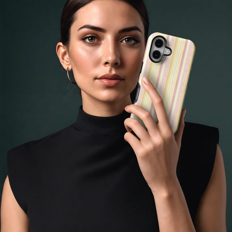 May include: A smartphone case with a vertical striped pattern in pastel colors of yellow, pink, and white. The case has a black camera lens cutout and is held in front of a person.