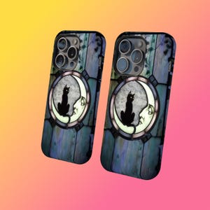 Puede incluir: Dos fundas para tel&eacute;fono con un dise&ntilde;o de vidriera que presenta un gato negro posado en una luna creciente. El fondo tiene un patr&oacute;n de vetas de madera azul y verde. Las fundas tienen un borde negro y un recorte para la c&aacute;mara.