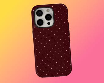 May include: A burgundy phone case with a white polka dot pattern. The case has a glossy finish and a camera cutout. The background is a gradient of yellow, orange, and pink.