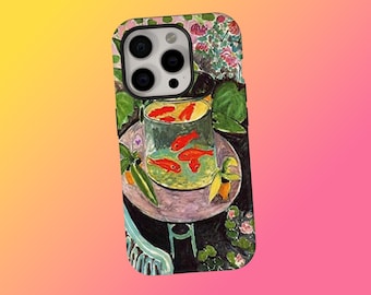Puede incluir: Funda de teléfono con una pintura de un cuenco de cristal con peces dorados sobre una mesa. La obra de arte incluye un fondo floral y una silla verde. La funda tiene un recorte de cámara negro y un fondo degradado rosa, amarillo y naranja.