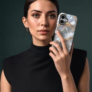 May include: A phone case with a pearlescent finish, featuring a swirling pattern in white, gold, and blue. The case has a glossy surface and protective edges. The phone case is held against a dark green backdrop.