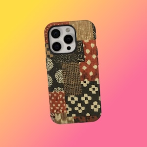 Può includere: Una custodia per telefono patchwork con una miscela di quadrati di tessuto fantasia nei toni del marrone, rosso e nero. La custodia ha un ritaglio per la fotocamera e un paraurti protettivo. Il design include motivi floreali, a pois e geometrici.