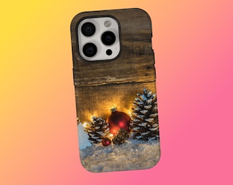 May include: A wooden phone case featuring a festive winter scene. The design includes pine cones, red ornaments, and a dusting of snow, all illuminated by soft, warm lights. The case has a dark wood grain texture.