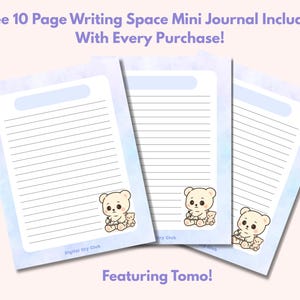 Op de afbeelding: Drie gelinieerde journaalpagina's met een lichtblauwe aquarel wasrand en een cartoon beer illustratie. De tekst bovenaan luidt "Free 10 Page Writing Space Mini Journal Included With Every Purchase!" en "Featuring Tomo!" onderaan.