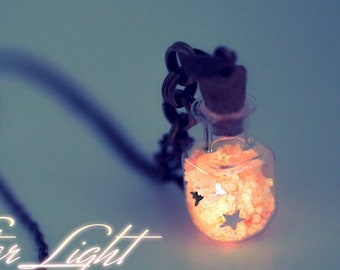 May include: A glass bottle necklace with a silver chain. The bottle is filled with white glitter and has a star-shaped charm. The text "Star Light" and "www.13thpsyche.com" is visible below the bottle.