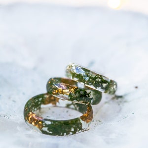 Nature stacking ring in clear resin with moss detail around the band, metal-free surface touching skin.