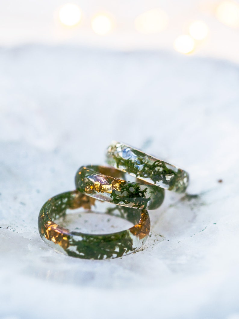 Nature stacking ring in clear resin with moss detail around the band, metal-free surface touching skin.