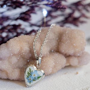 Silver tone pressed flower heart pendant locket shown open with space for tiny photo note