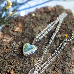 Silver tone pressed flower heart pendant locket shown open with space for tiny photo note