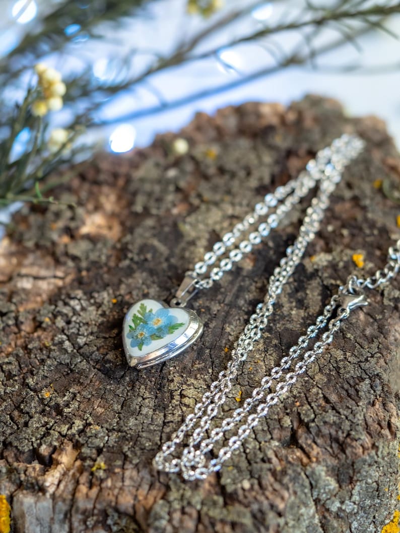 Silver tone pressed flower heart pendant locket shown open with space for tiny photo note