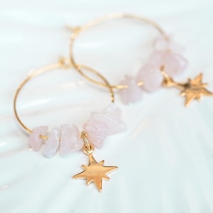 May include: Gold hoop earrings with pink rose quartz stones and a gold star charm.