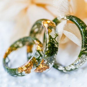 Nature stacking ring in clear resin with moss detail around the band, metal-free surface touching skin.