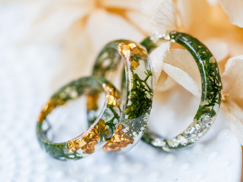 Nature stacking ring in clear resin with moss detail around the band, metal-free surface touching skin.