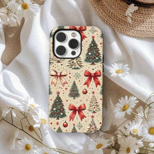 May include: A phone case with a festive Christmas theme. The case features a repeating pattern of Christmas trees, red bows, snowflakes, and ornaments on a cream-colored background. The case is designed to fit a smartphone.
