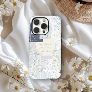May include: A phone case with a patchwork design in shades of blue and white. The case features floral and geometric patterns, with the text "may Jesus be seen in me in spite of me".