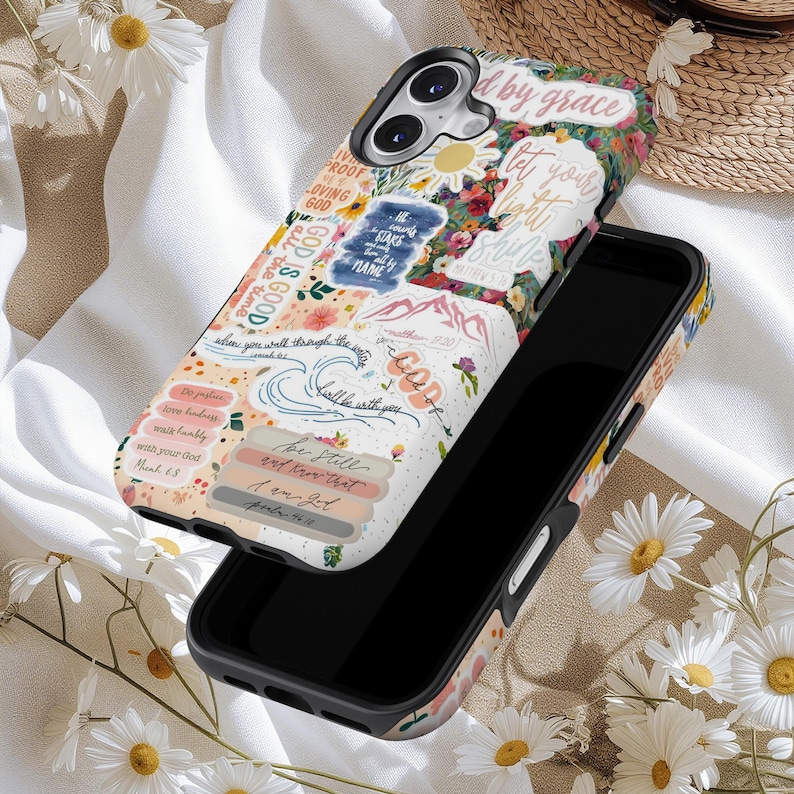 May include: A black smartphone case with a floral and scripture design. The case features a collage of colorful flowers and inspirational quotes. The text includes phrases like "God is Good" and "Let your light shine".